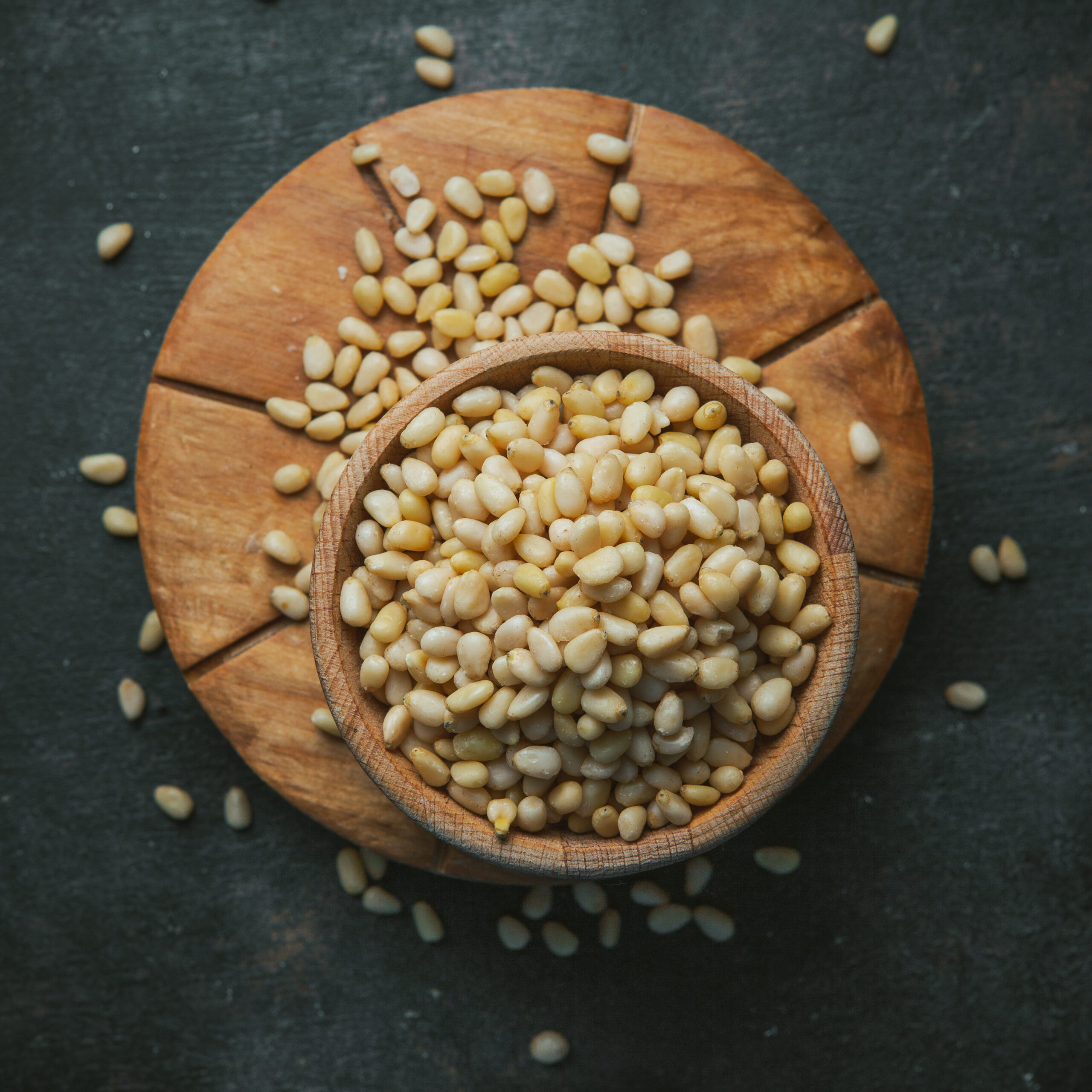 Grains in a wooden bowl on wooden piece and dark background. top view.