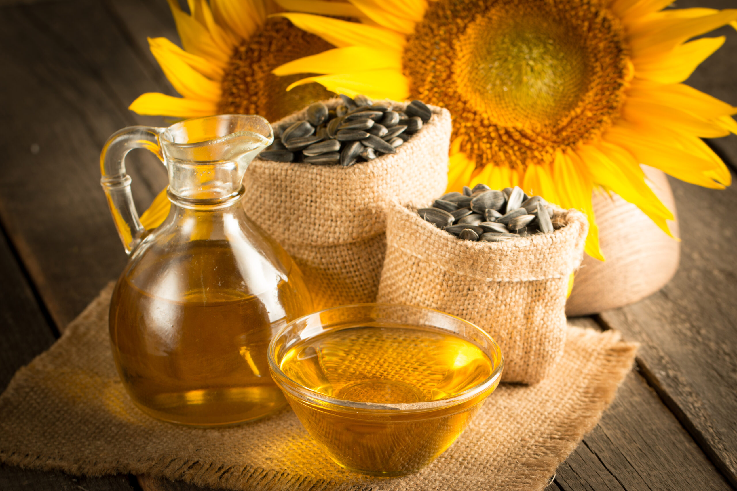 Closeup photo of sunflower oil with seeds on wooden background. Bio and organic product concept.