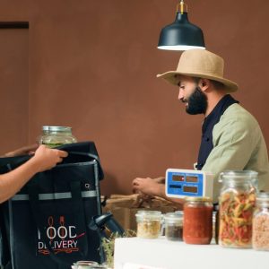 Deliveryman taking food supplies order with backpack to deliver organic freshly harvested produce to local clients. Employees preparing fruits and vegetables, sustainable lifestyle. Tripod shot.